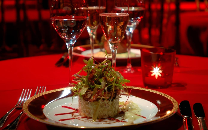 Elegant dinner setting at Rojo Tango Show with gourmet dish and wine glasses.