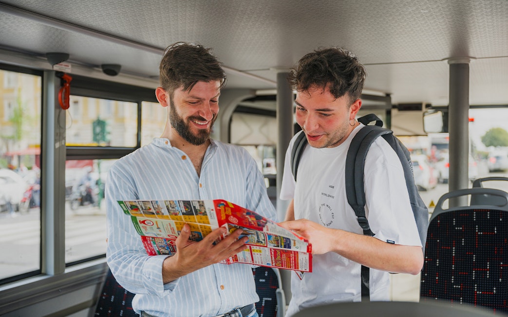 Tourists reading a map on a bus during a Rome night tour.
