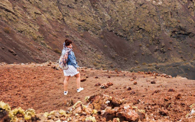 Person hiking on volcanic terrain at Timanfaya National Park, Lanzarote.