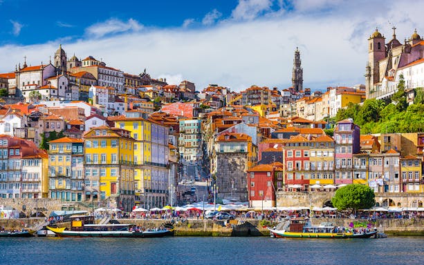 Colorful buildings along the Douro River in Porto, Portugal, with boats and historic architecture.