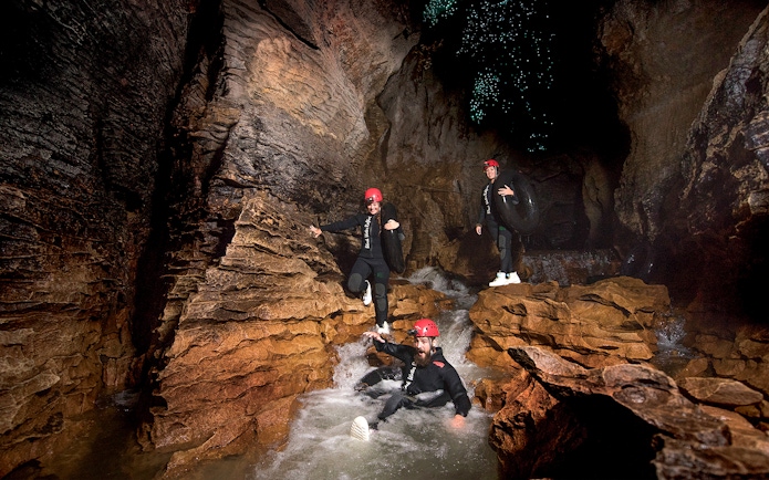Adventurers black water rafting in Waitomo cave with glowworms above.
