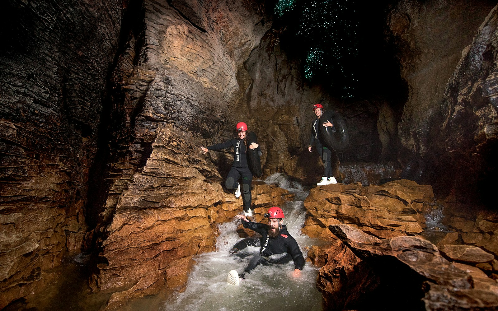 Adventurers black water rafting in Waitomo cave with glowworms above.