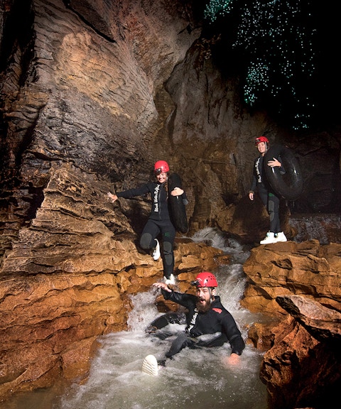 Adventurers black water rafting in Waitomo cave with glowworms above.