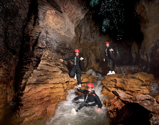 Adventurers black water rafting in Waitomo cave with glowworms above.