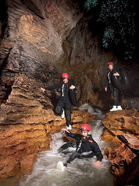 Adventurers black water rafting in Waitomo cave with glowworms above.