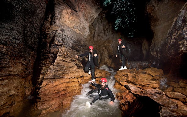 Adventurers black water rafting in Waitomo cave with glowworms above.