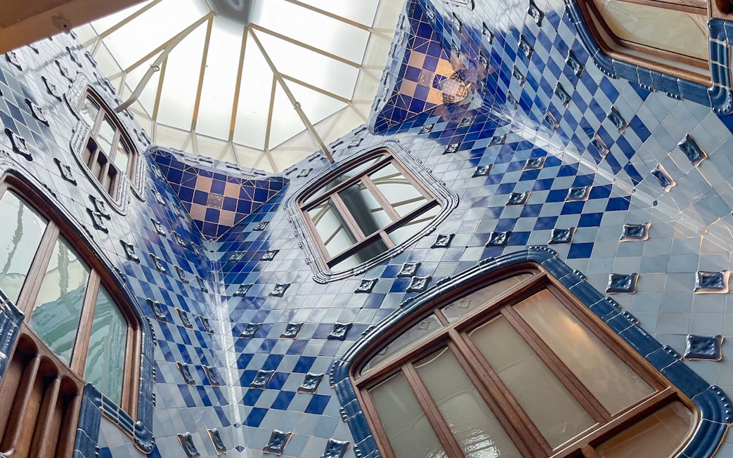 Casa Batlló interior with blue tiled walls and skylight in Barcelona.