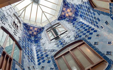 Casa Batlló interior with blue tiled walls and skylight in Barcelona.