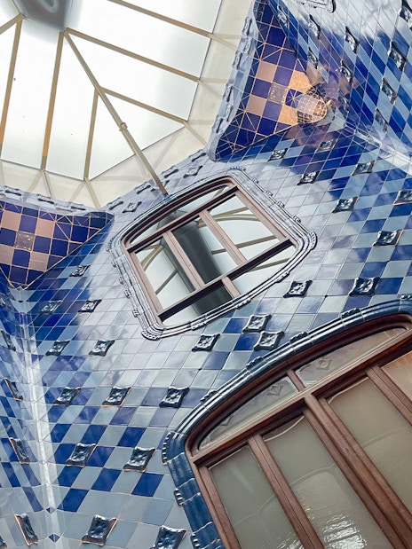 Casa Batlló interior with blue tiled walls and skylight in Barcelona.