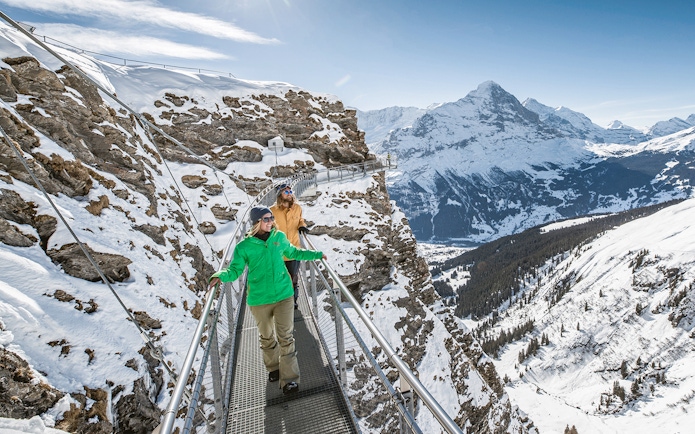 Visitors walking on Grindelwald First Cliff Walk with Eiger mountain view.