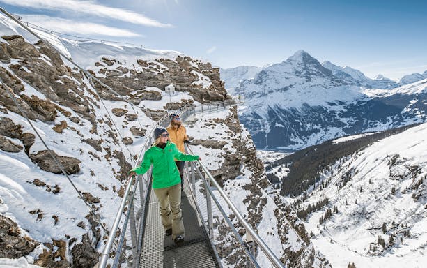 Visitors walking on Grindelwald First Cliff Walk with Eiger mountain view.