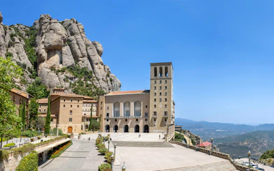 Abbey of Montserrat with mountain backdrop and courtyard in Catalonia, Spain.