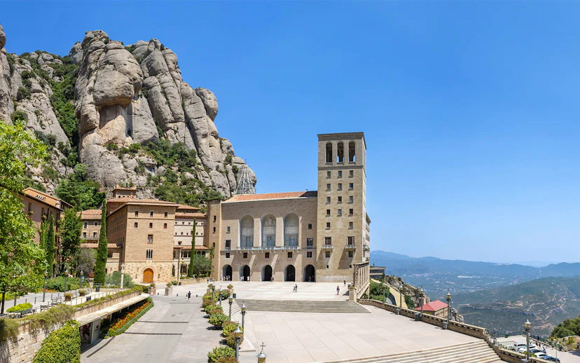 Abbey of Montserrat with mountain backdrop and courtyard in Catalonia, Spain.