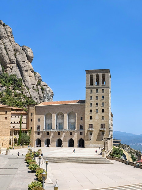 Abbey of Montserrat with mountain backdrop and courtyard in Catalonia, Spain.