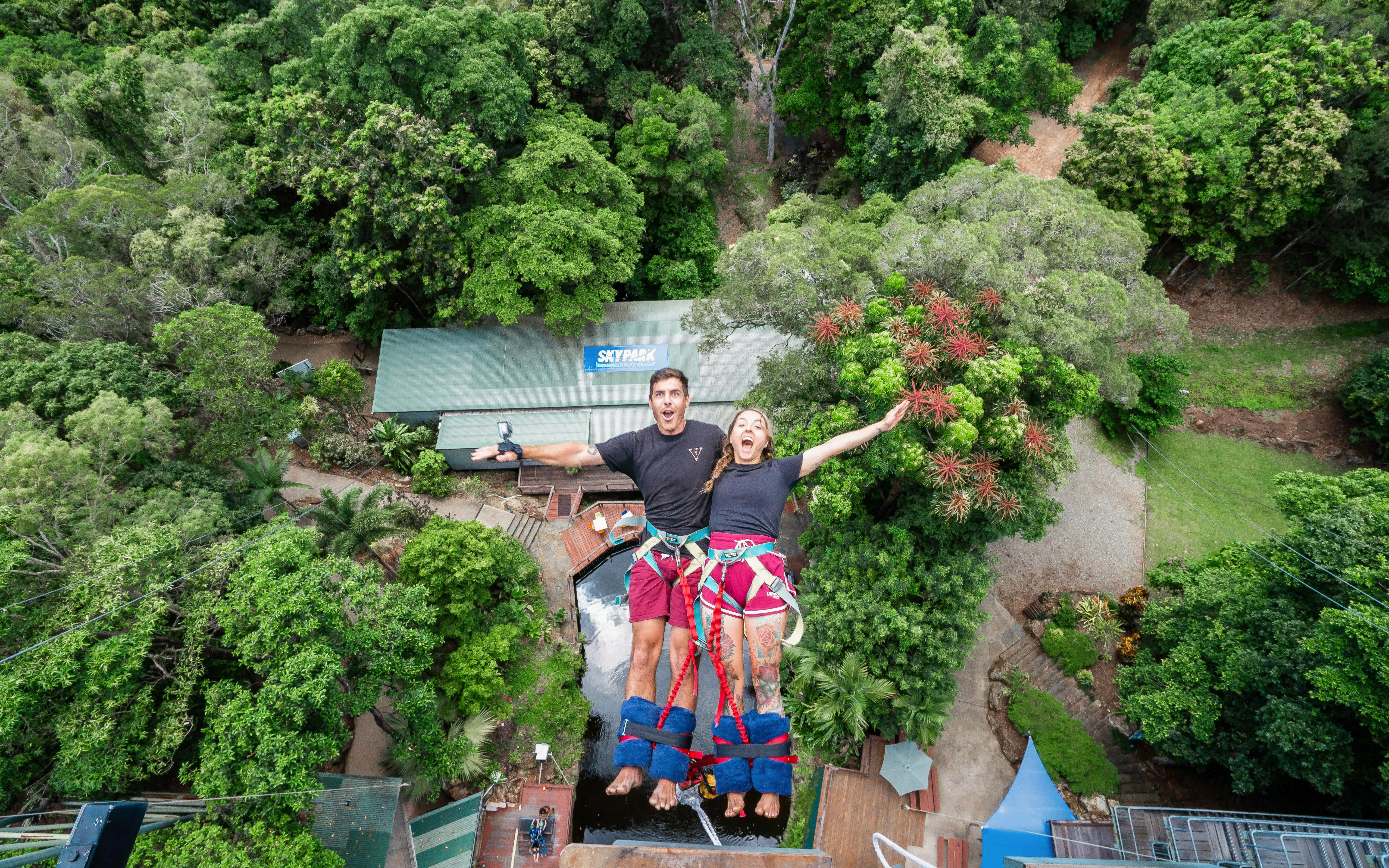 Visitors tandem back diving at Skypark Cairns amidst lush greenery.