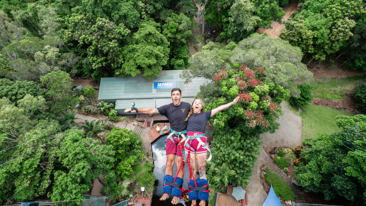 Visitors tandem back diving at Skypark Cairns amidst lush greenery.