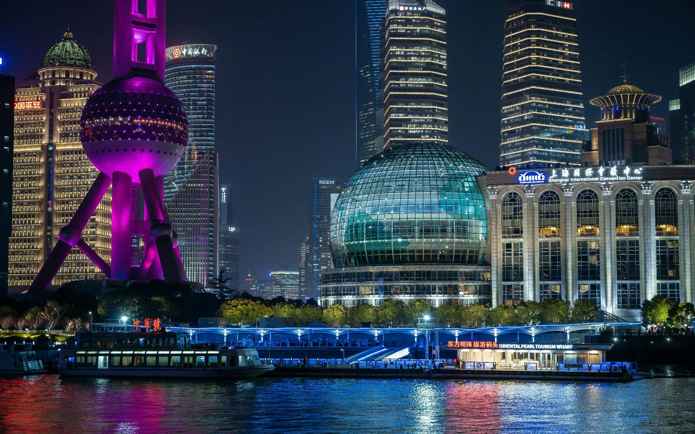 Cruise on Huangpu River past Shanghai's Oriental Pearl Tower and skyline at night.