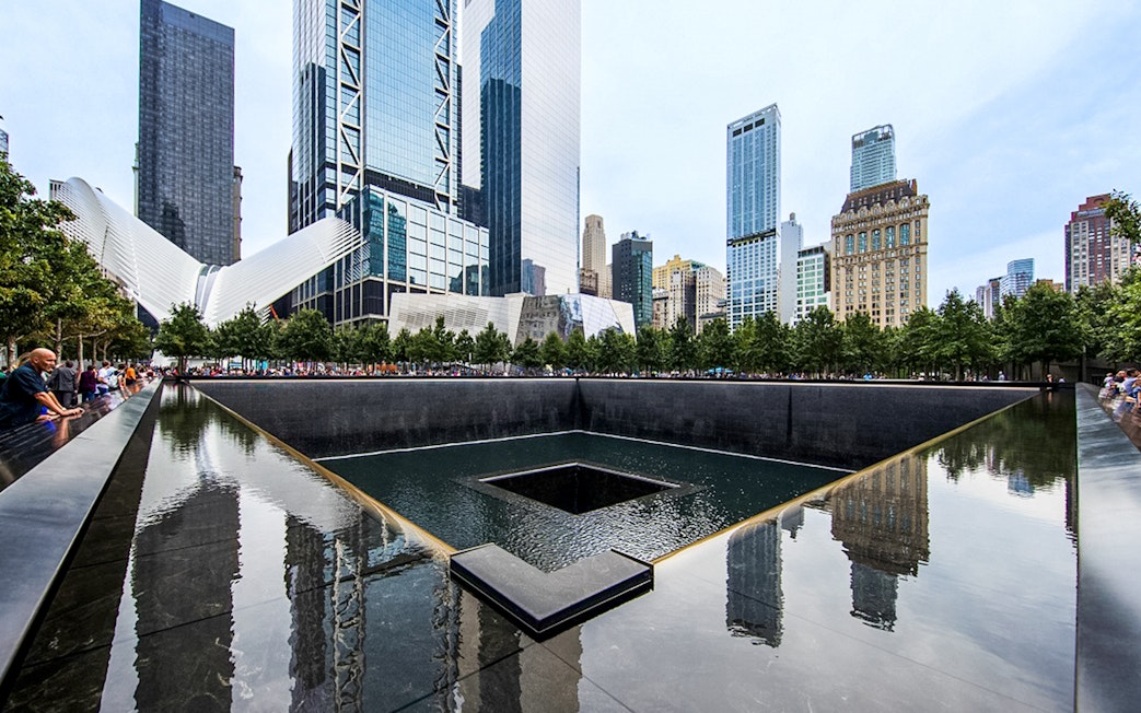 Reflecting pool at the 9/11 Memorial in New York City with surrounding skyscrapers.
