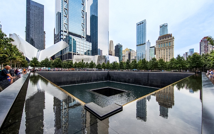 Reflecting pool at the 9/11 Memorial in New York City with surrounding skyscrapers.