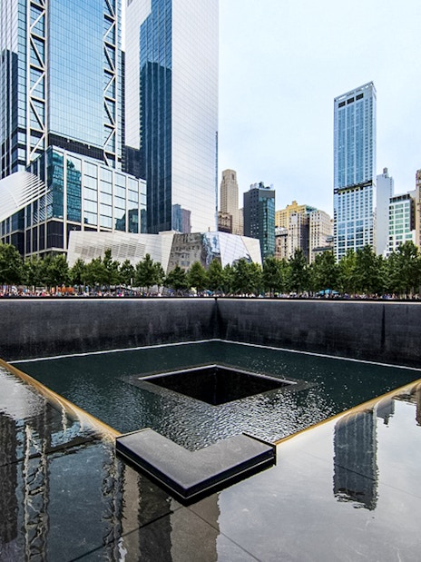 Reflecting pool at the 9/11 Memorial in New York City with surrounding skyscrapers.