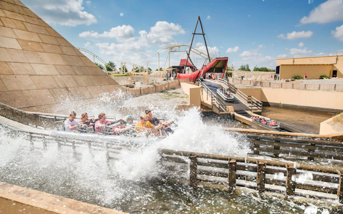 Guests on a water ride at BELANTIS Adventure Park with splashing waves.