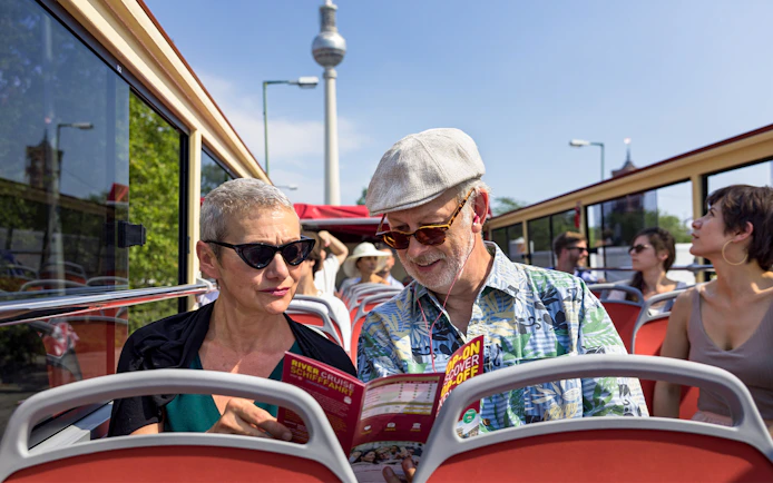 Couple on Berlin BigBus tour reading route map with TV Tower in background.