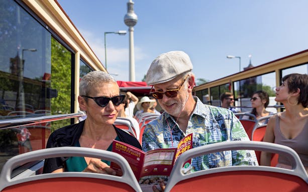 Couple on Berlin BigBus tour reading route map with TV Tower in background.