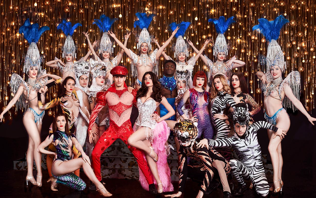 Cabaret performers in vibrant costumes on stage, Paris New Year's Eve show.