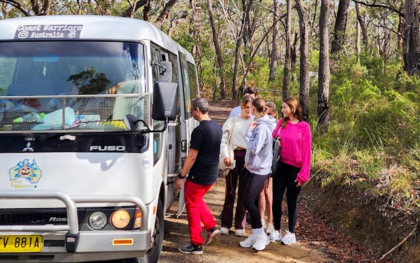 People boarding a tour bus in the Blue Mountains forest area.
