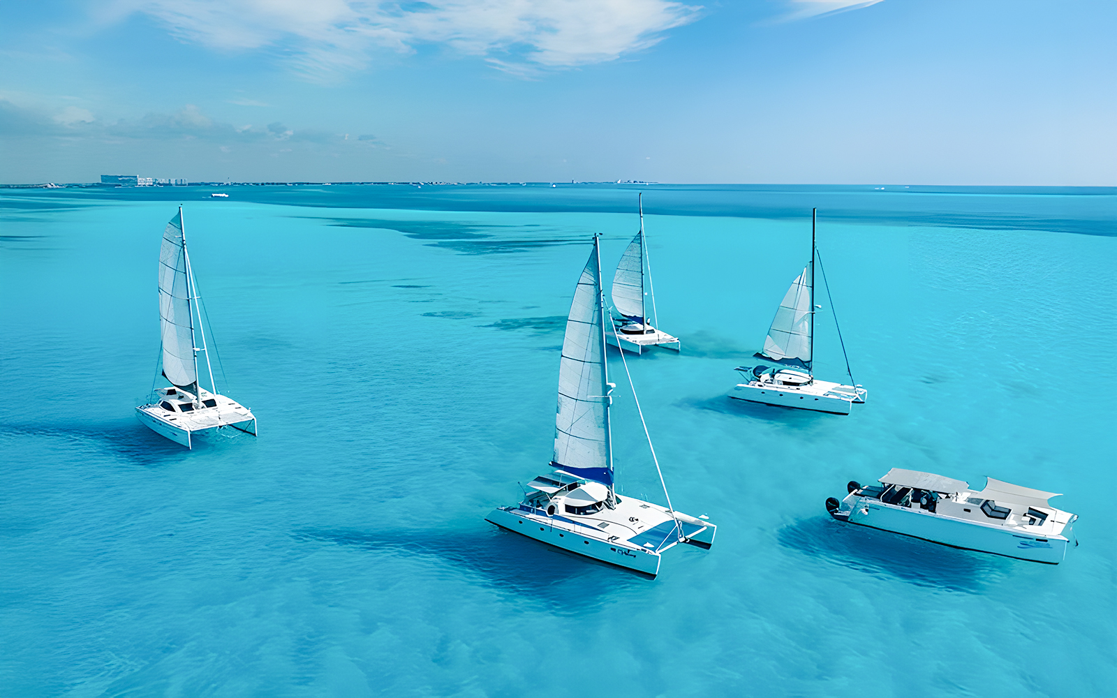 Catamarans sailing in turquoise Caribbean Sea near Cancún, Mexico coastline.