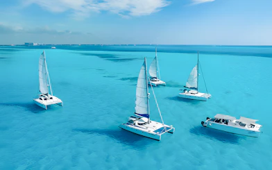 Catamarans sailing in turquoise Caribbean Sea near Cancún, Mexico coastline.