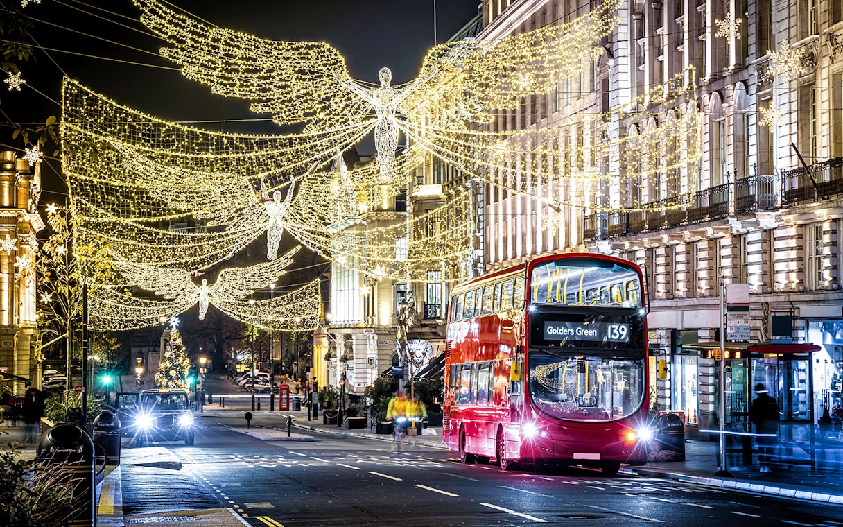 London Christmas lights with red double-decker bus on night tour.