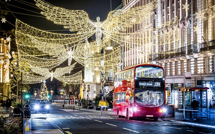 London Christmas lights with red double-decker bus on night tour.