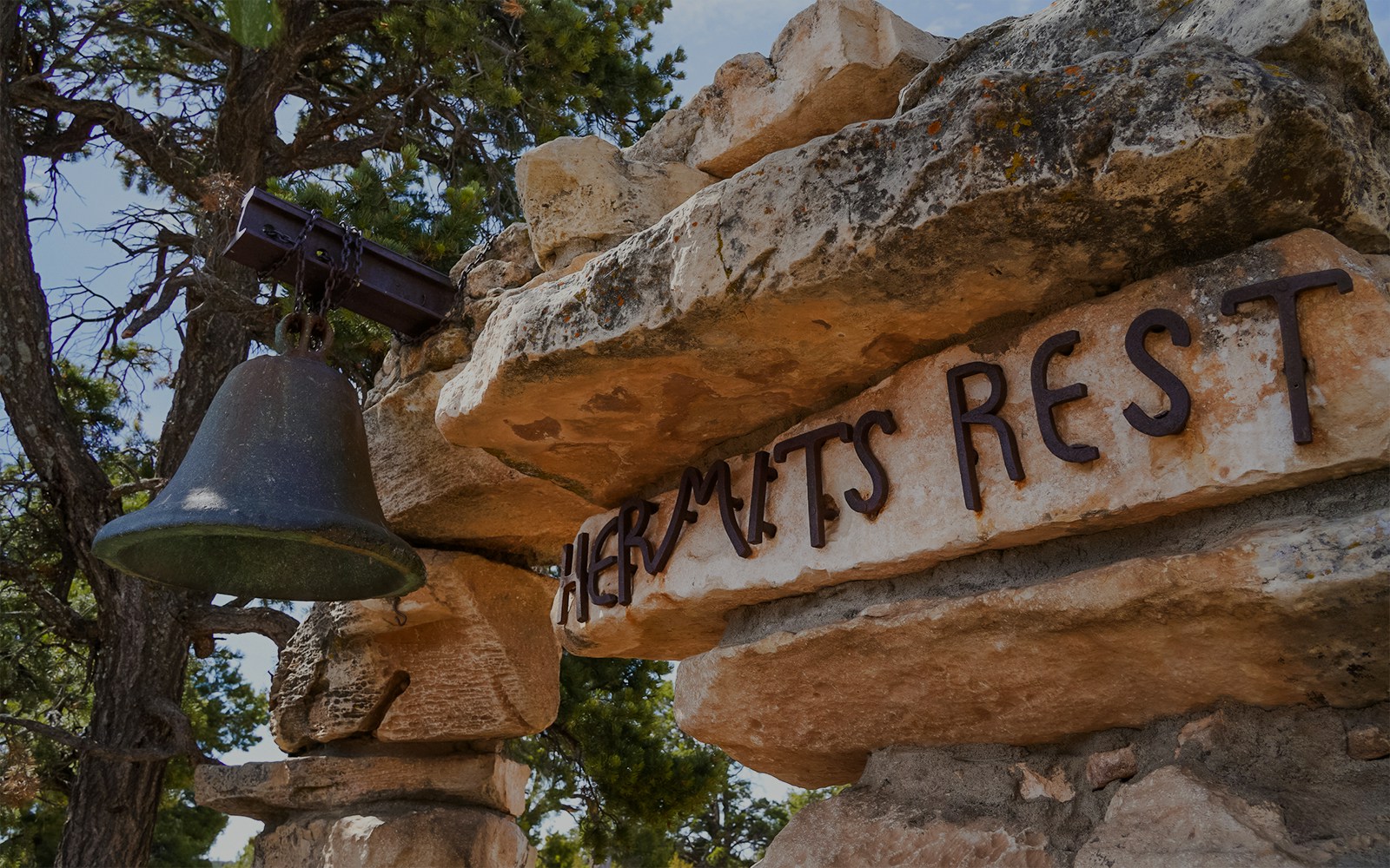 Hermits Rest stone structure with bell tower at Grand Canyon, Arizona, surrounded by trees and rocky landscape.