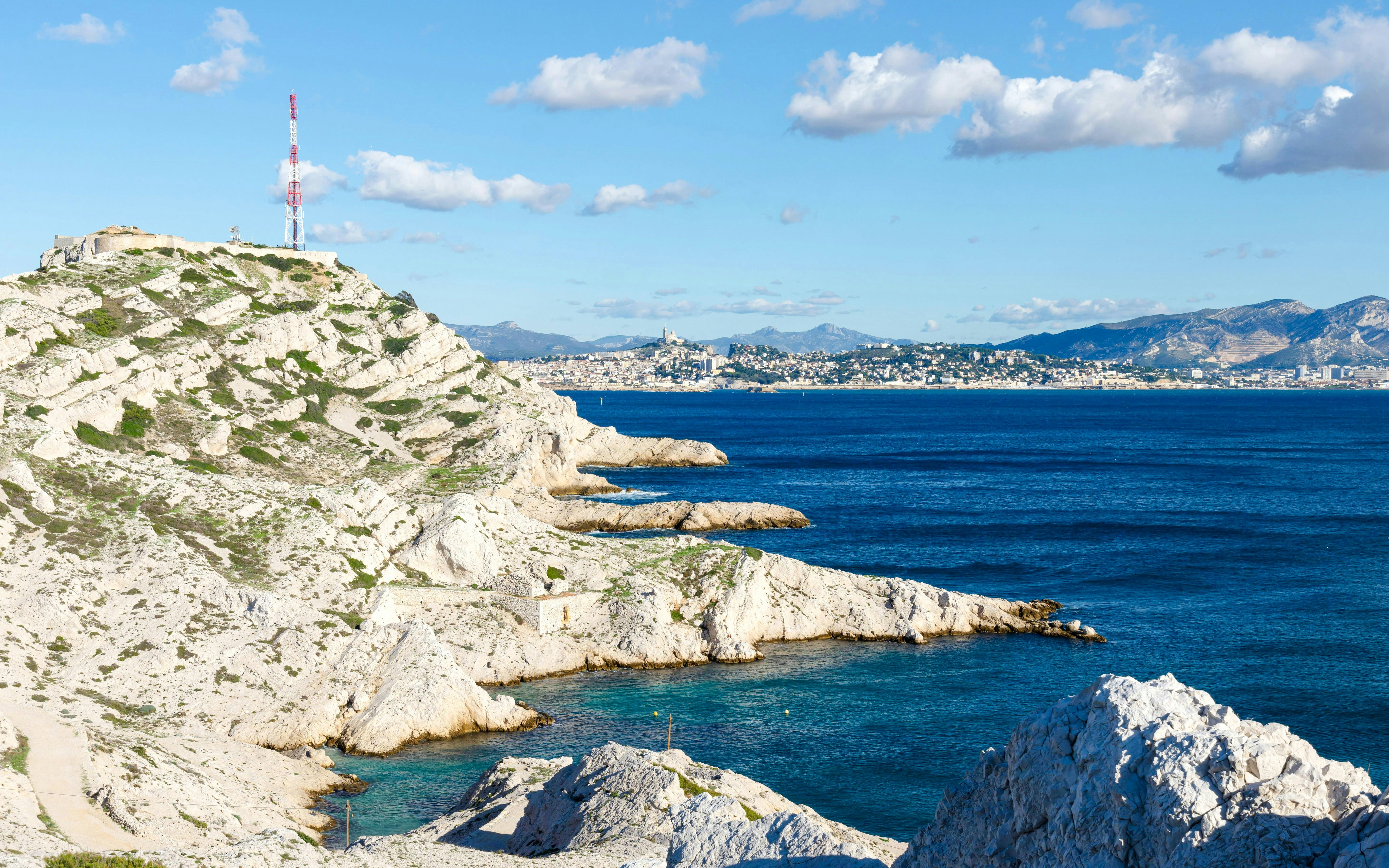 Rocky coastline of Pomègues Island with view of Marseille in the distance.