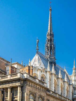 Sainte Chapelle spire and facade against blue sky in Paris, France.