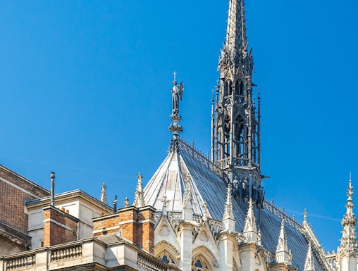 Sainte Chapelle spire and facade against blue sky in Paris, France.