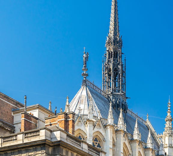 Sainte Chapelle spire and facade against blue sky in Paris, France.