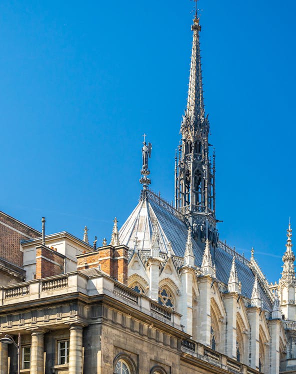 Sainte Chapelle spire and facade against blue sky in Paris, France.