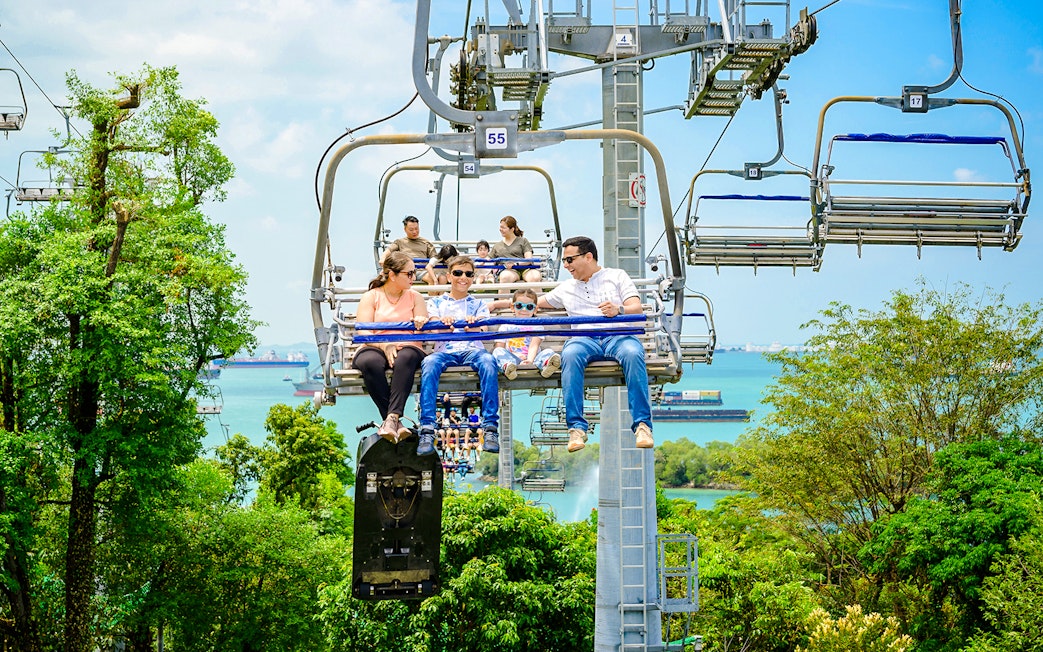 Family enjoying the Skyride over lush greenery and ocean views in Singapore.