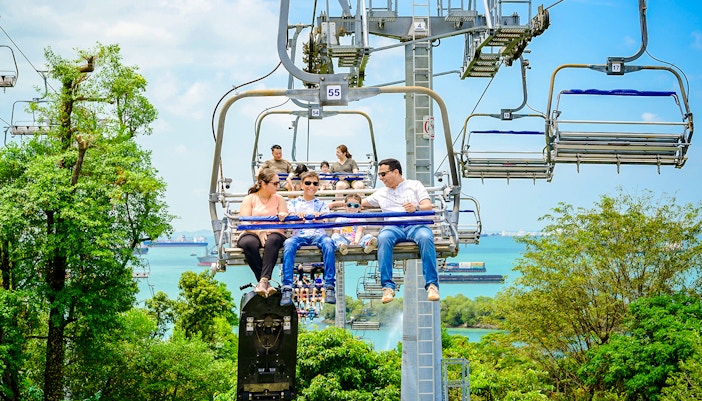 Family enjoying the Skyride over lush greenery and ocean views in Singapore.