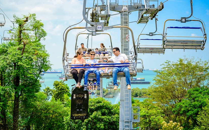 Family enjoying the Skyride over lush greenery and ocean views in Singapore.