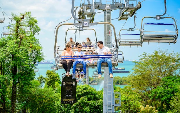 Family enjoying the Skyride over lush greenery and ocean views in Singapore.