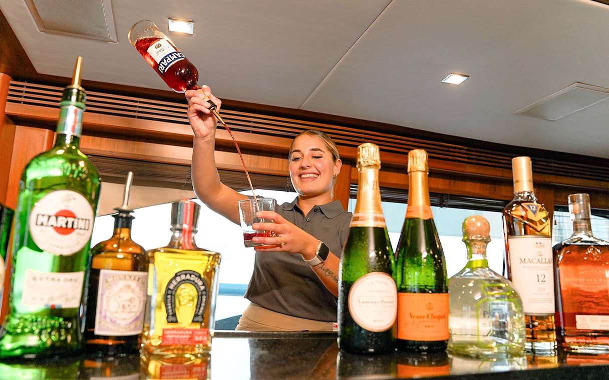 Bartender preparing a cocktail on a Sunseeker superyacht with premium spirits and champagne.