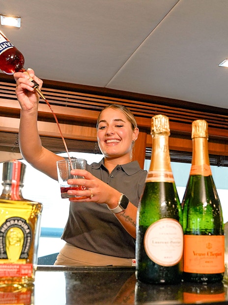 Bartender preparing a cocktail on a Sunseeker superyacht with premium spirits and champagne.