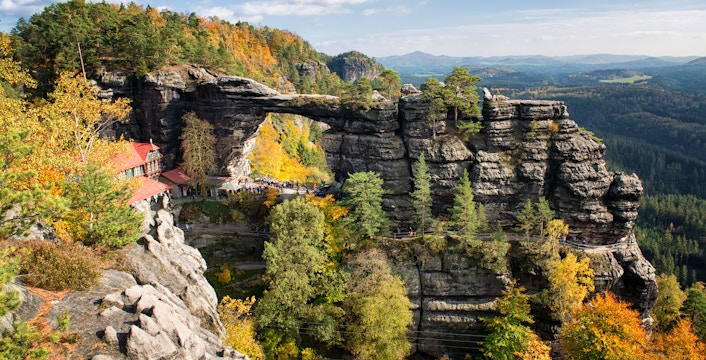 Pravčická Brána rock arch surrounded by autumn foliage in Bohemian Switzerland.