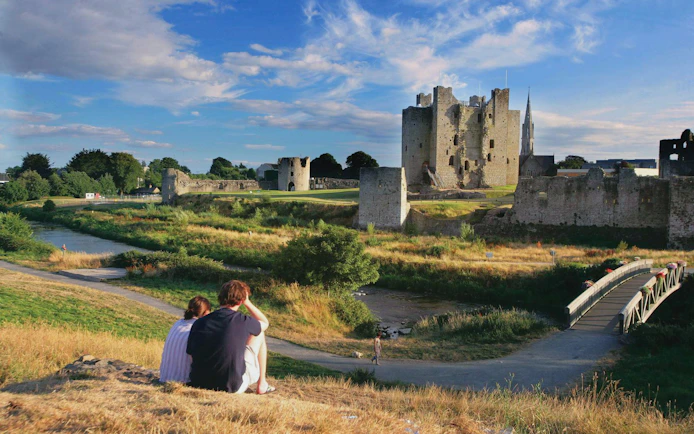 Couple sitting on a hill overlooking Trim Castle in County Meath, Ireland.