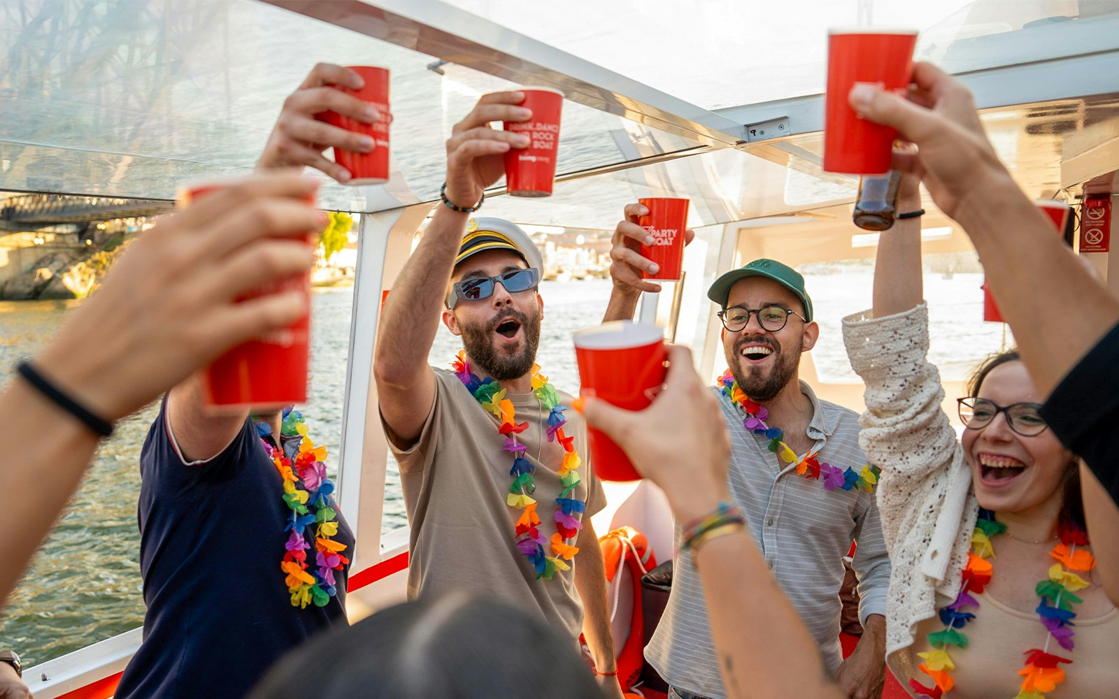 Partygoers with drinks and leis on a Douro River cruise in Porto, Portugal.