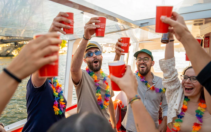 Partygoers with drinks and leis on a Douro River cruise in Porto, Portugal.