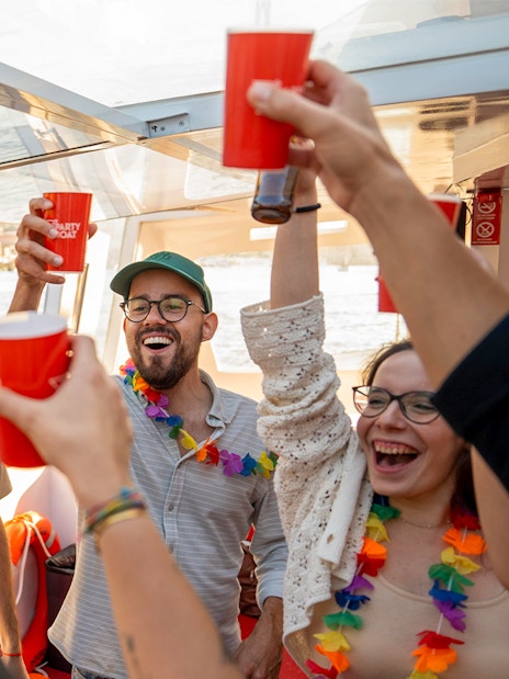Partygoers with drinks and leis on a Douro River cruise in Porto, Portugal.